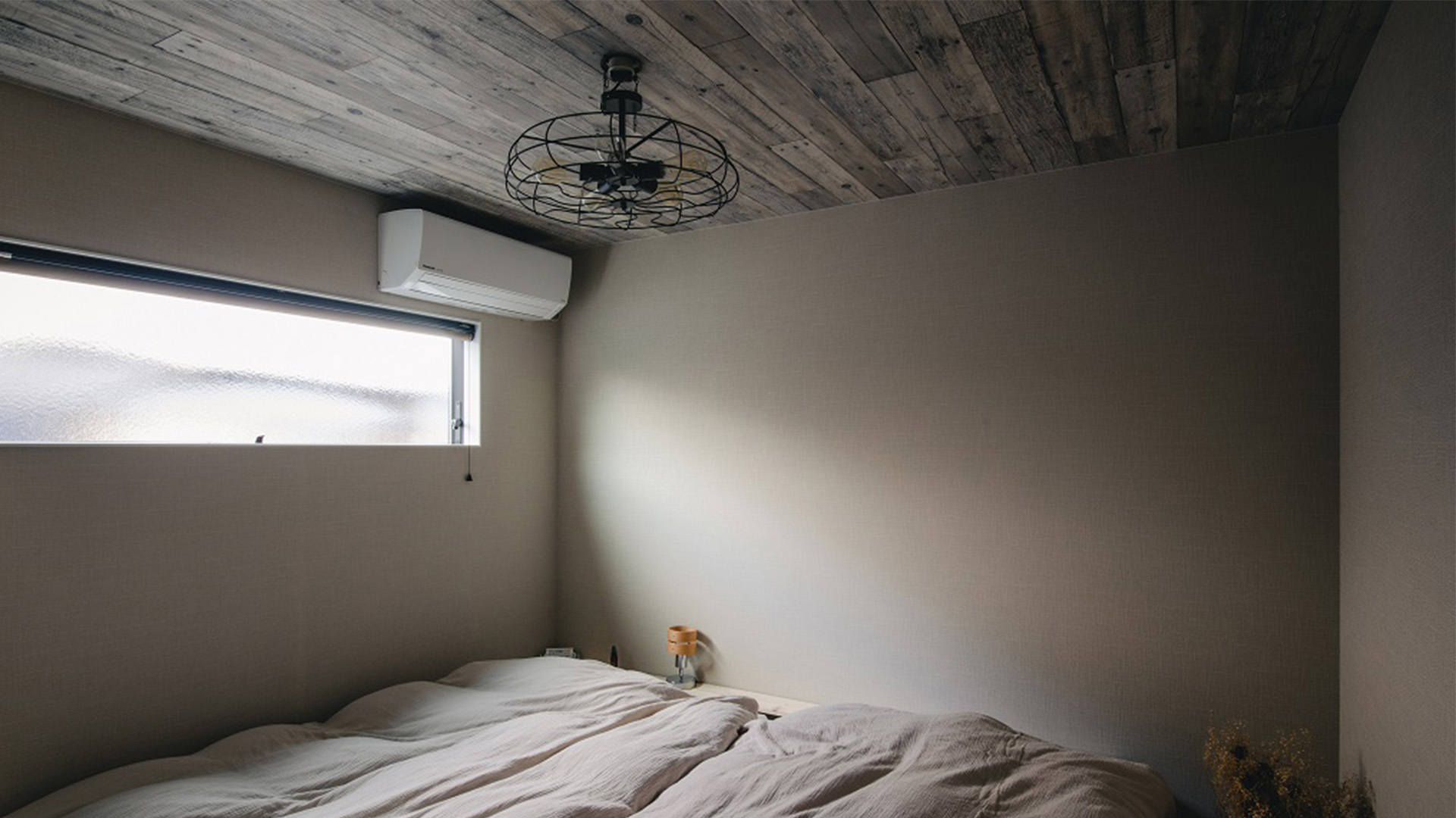 インダストリアルな雰囲気でアイアンの扇風機がワンポイントとなっている寝室の画像。