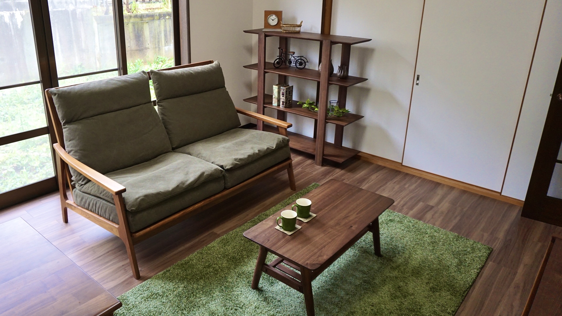 愛知県豊橋市飯村のリノベ一軒家のソファーとローテーブルとシェルフとラグマットの画像